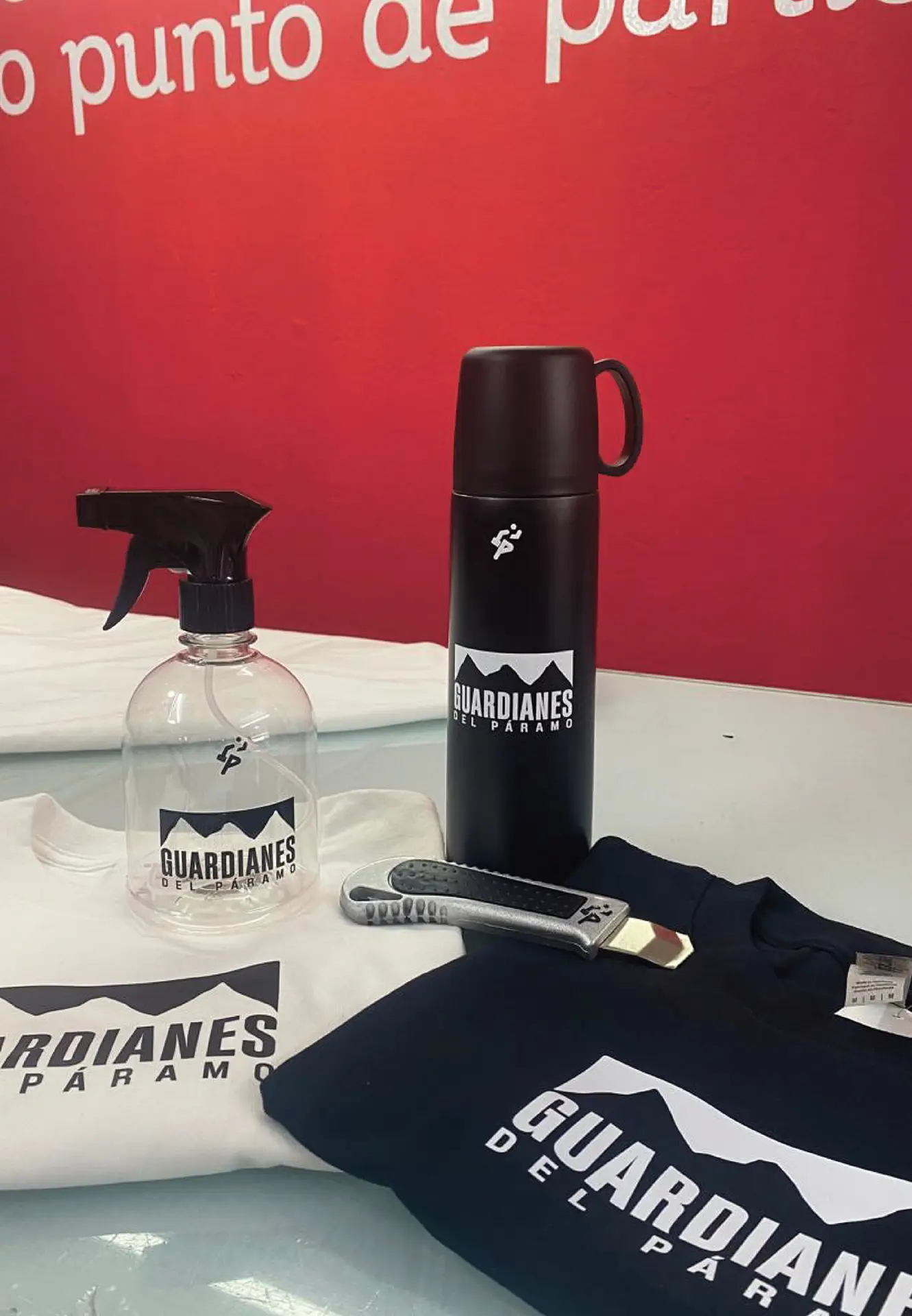 Kit de souvenirs personalizados para Guardianes del Páramo: incluye camisetas estampadas, termo metálico negro mate, atomizador y bisturí de seguridad, todos marcados por Bresspop Publicidad.