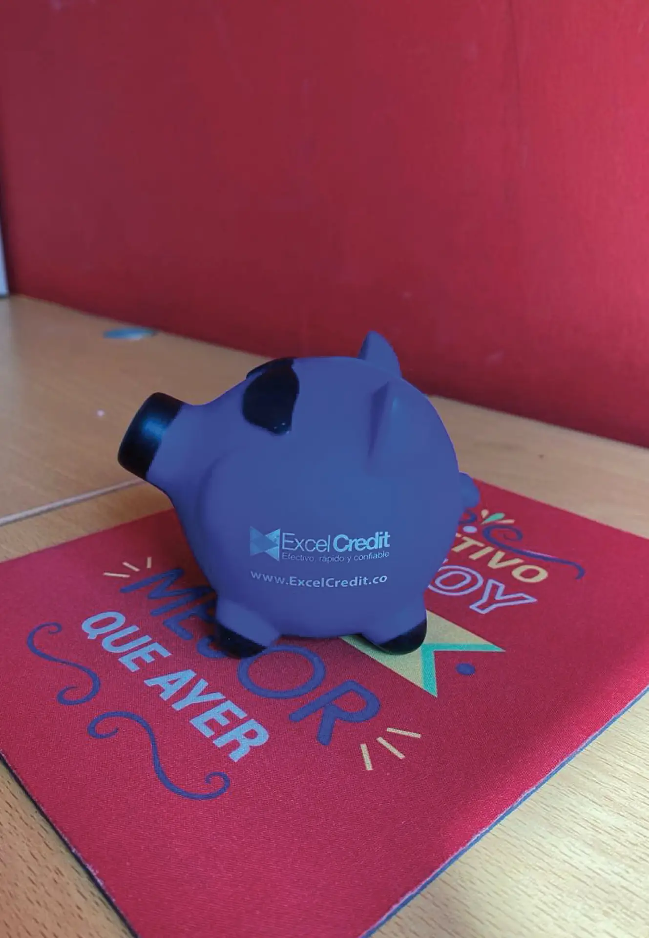 Souvenir corporativo personalizado para ExcelCredit: alcancía tipo cerdito antiestrés en color morado con impresión de marca, diseñado y distribuido por Bresspop Publicidad.